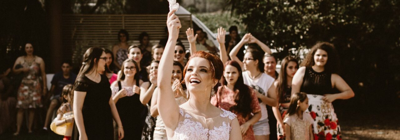 bride throwing flower bouquet on women during daytime